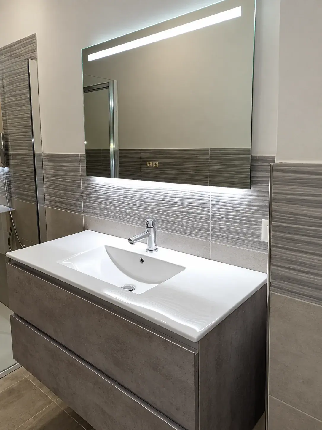Lavabo sospeso con specchio illuminato e rivestimento a onde