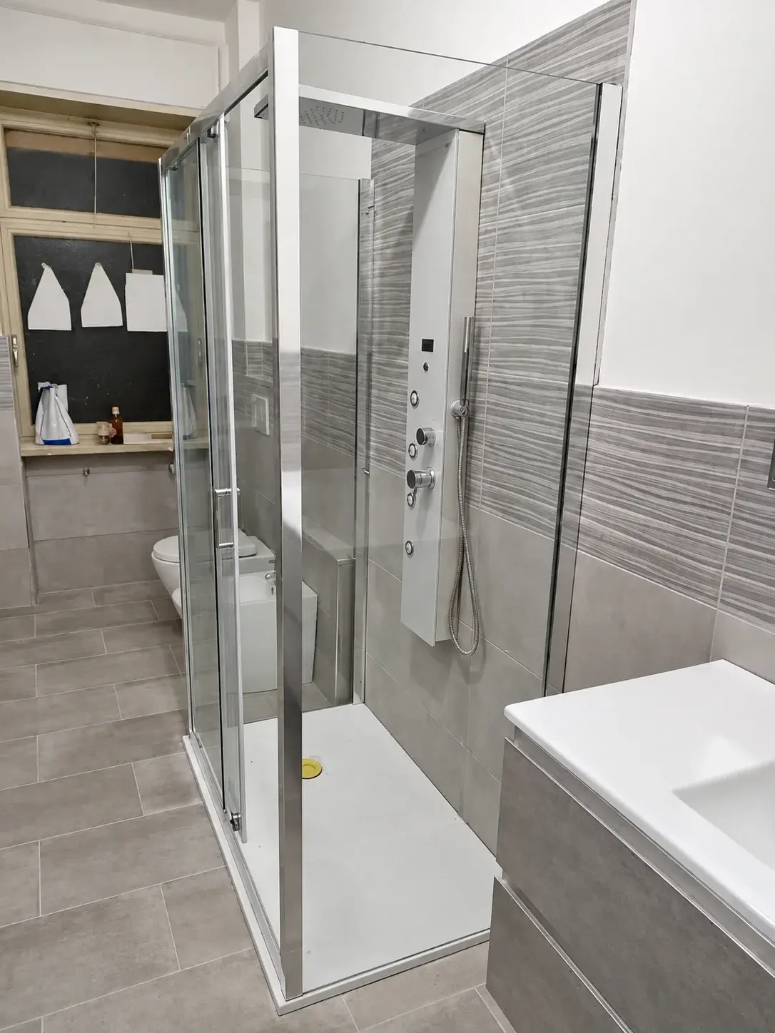 Bagno con box doccia e rivestimenti a rilievo alle pareti